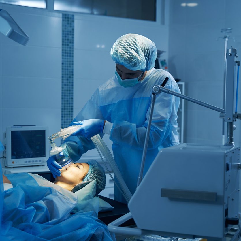 Young woman lying on the operation table with her eyes closed and getting anesthesia