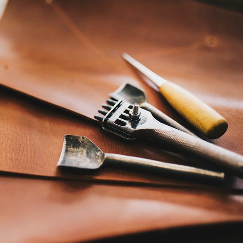 Crafting tools on natural cow leather in the tailoring workshop. Top view.